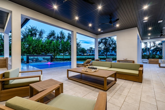 patio terrace at dusk featuring ceiling fan and an outdoor hangout area