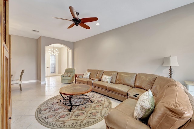 tiled living room with ceiling fan with notable chandelier