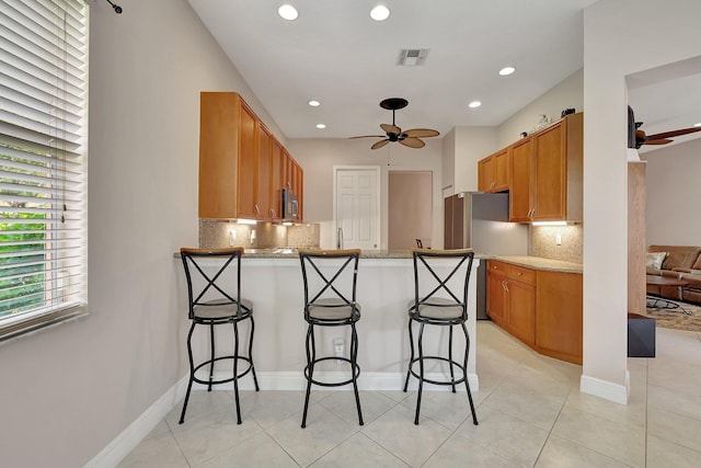 kitchen featuring appliances with stainless steel finishes, a breakfast bar, ceiling fan, and kitchen peninsula