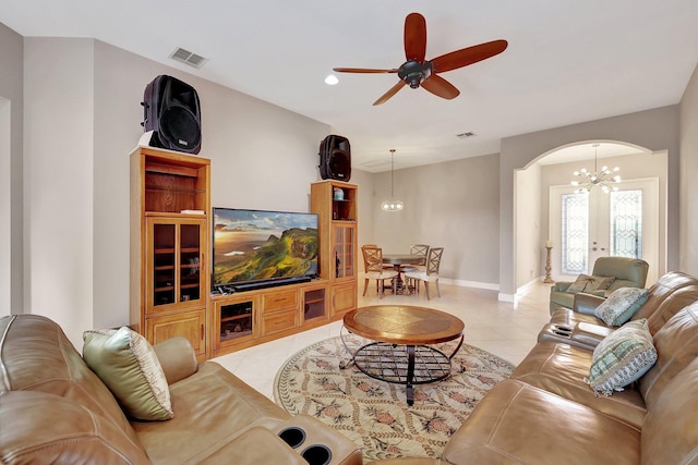 tiled living room featuring ceiling fan with notable chandelier and french doors