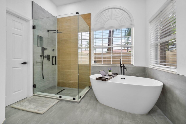 bathroom with independent shower and bath, a wealth of natural light, and tile walls