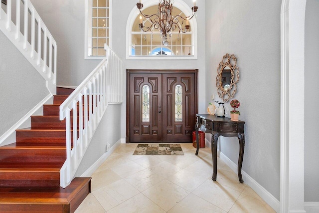 tiled foyer entrance featuring a notable chandelier and a towering ceiling