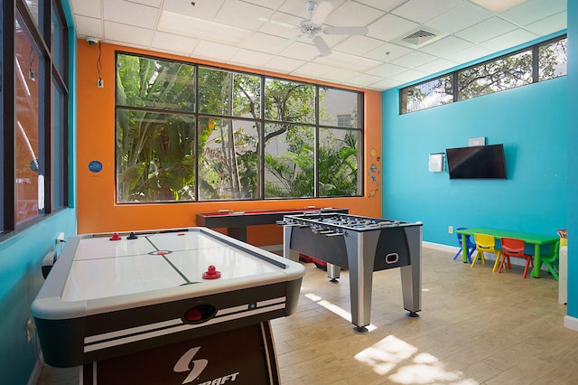 game room featuring ceiling fan, a drop ceiling, and light hardwood / wood-style flooring