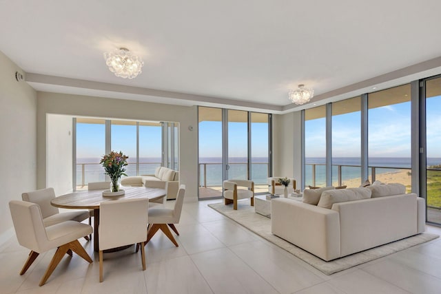 living room with light tile patterned floors, a water view, an inviting chandelier, and expansive windows