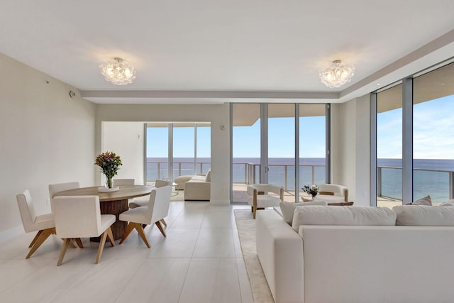 living room featuring light tile patterned floors, a water view, and an inviting chandelier