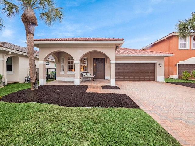 mediterranean / spanish house featuring covered porch, a garage, and a front lawn