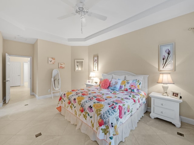 tiled bedroom with ceiling fan and a raised ceiling