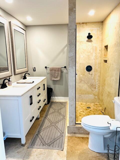 bathroom featuring a tile shower, vanity, tile patterned flooring, and toilet