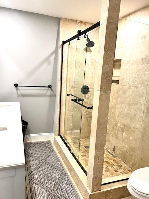 bathroom with a tile shower and toilet