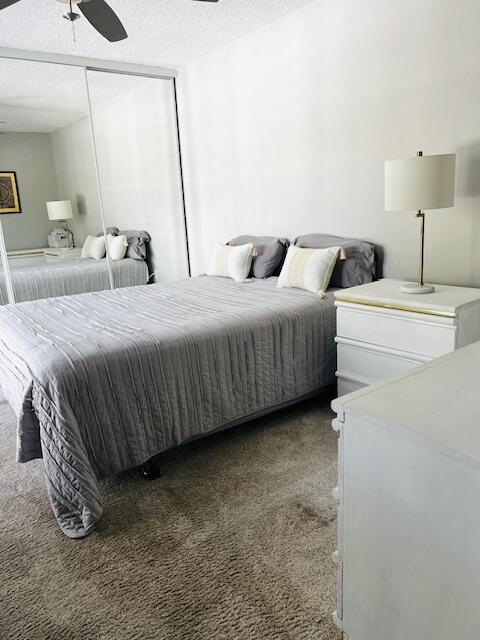 carpeted bedroom featuring ceiling fan and a textured ceiling