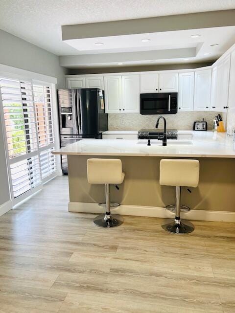 kitchen with decorative backsplash, a kitchen breakfast bar, light hardwood / wood-style floors, and white cabinetry