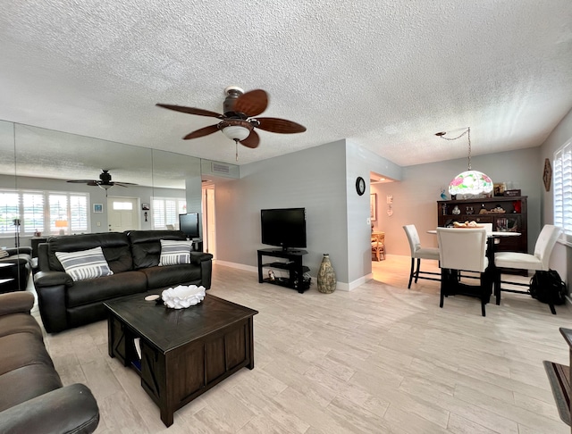 living room featuring ceiling fan, a textured ceiling, and light wood-type flooring