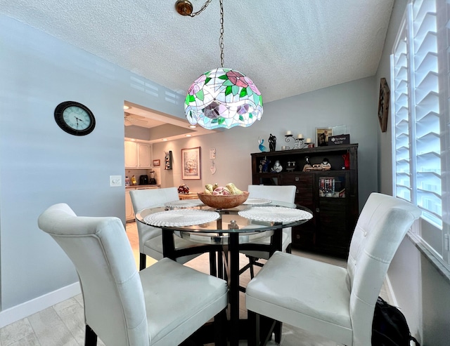 dining area with a textured ceiling and light hardwood / wood-style flooring