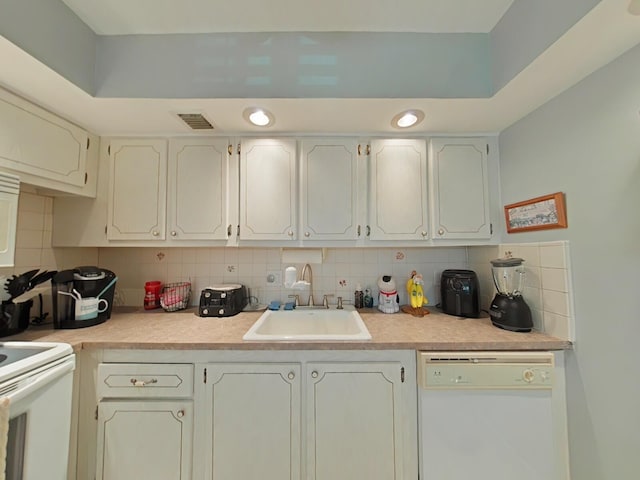 kitchen with tasteful backsplash, white cabinetry, sink, and white appliances