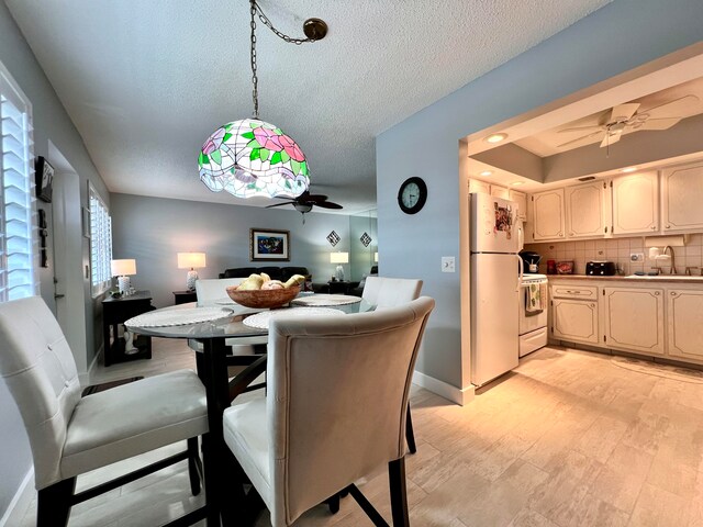 dining space featuring a textured ceiling, ceiling fan, and sink