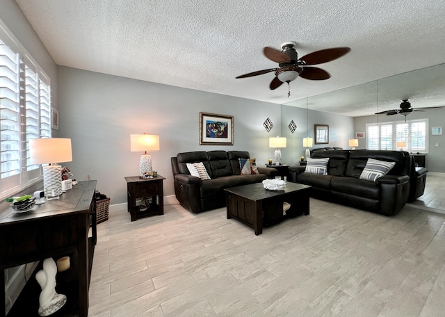 living room with ceiling fan, light hardwood / wood-style flooring, and a textured ceiling