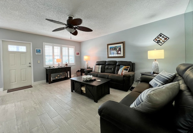 living room featuring ceiling fan, light hardwood / wood-style floors, and a textured ceiling