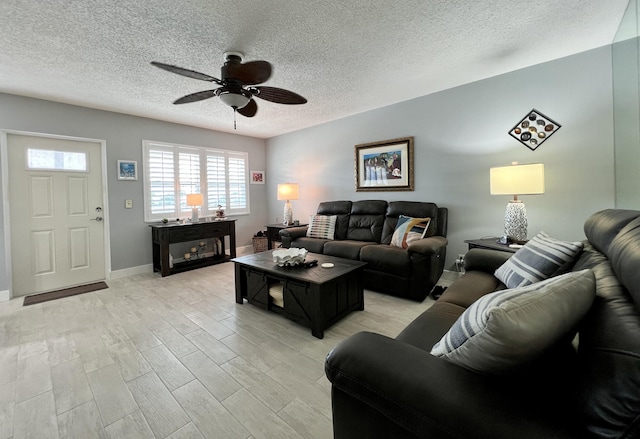 living room featuring ceiling fan, light hardwood / wood-style flooring, and a textured ceiling