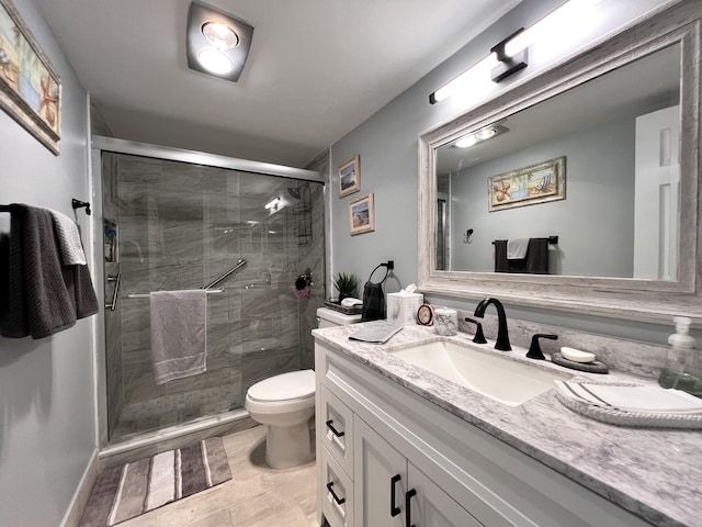 bathroom with vanity, a shower with door, and toilet