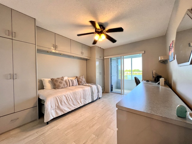 bedroom with access to exterior, ceiling fan, light hardwood / wood-style flooring, and a textured ceiling