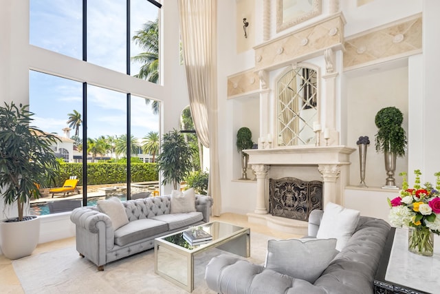 living room featuring a premium fireplace, light tile patterned flooring, and a high ceiling