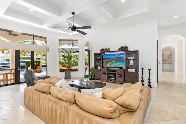 tiled living room featuring beamed ceiling, ornamental molding, coffered ceiling, and ceiling fan