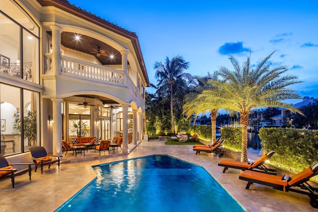 pool at dusk featuring a patio and ceiling fan