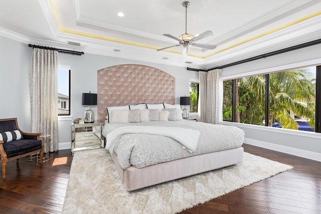 bedroom featuring ceiling fan, dark wood-type flooring, and a tray ceiling