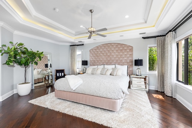 bedroom with a tray ceiling, ceiling fan, crown molding, and dark wood-type flooring