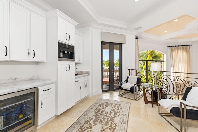 kitchen featuring white cabinetry, a tray ceiling, beverage cooler, ornamental molding, and light stone countertops