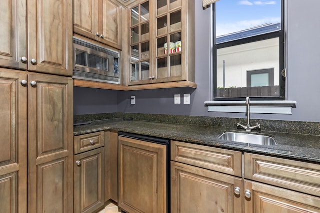 kitchen with dark stone countertops, sink, and stainless steel microwave