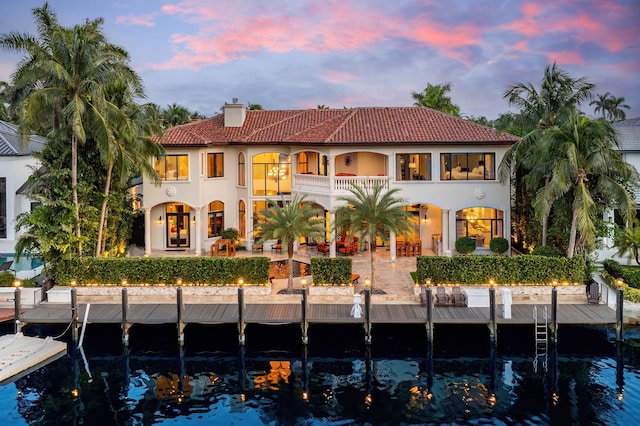 back house at dusk with a balcony and a patio