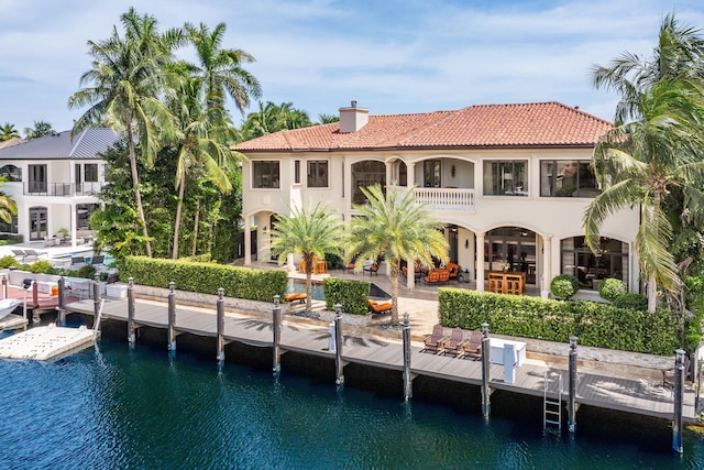 rear view of property featuring a balcony, a water view, and a patio