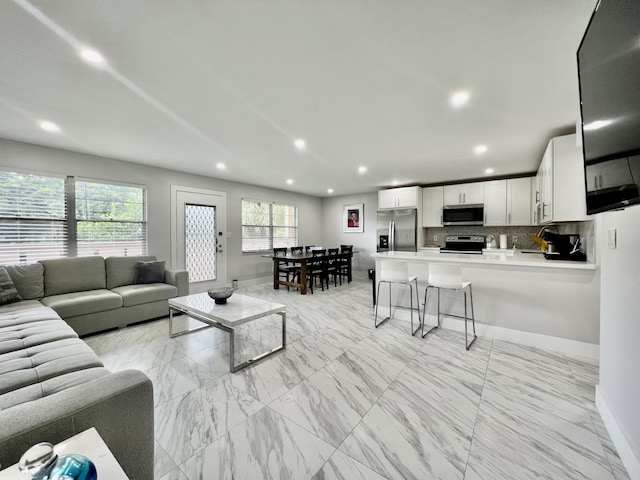 living area featuring baseboards, marble finish floor, and recessed lighting