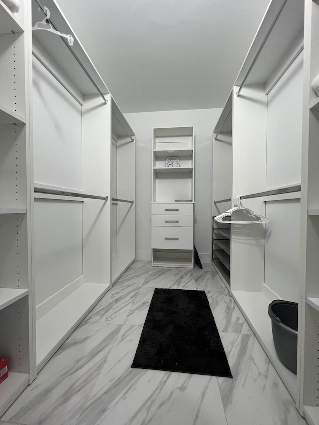 walk in closet featuring marble finish floor