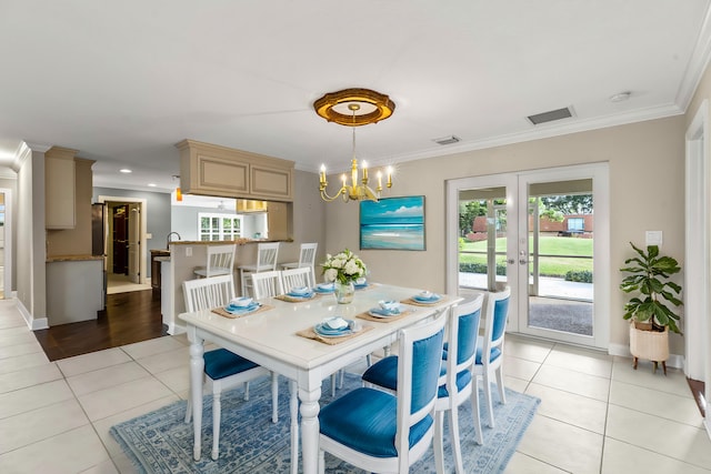 dining room featuring crown molding, an inviting chandelier, french doors, and light tile patterned floors