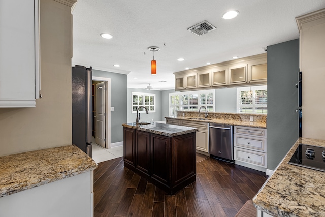 kitchen with sink, a kitchen island with sink, hanging light fixtures, stainless steel appliances, and dark hardwood / wood-style flooring