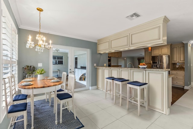 kitchen with decorative light fixtures, ornamental molding, stainless steel fridge, kitchen peninsula, and cream cabinets