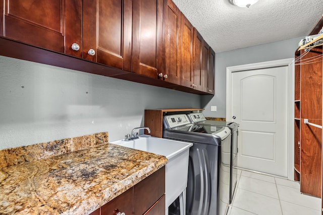 laundry room featuring cabinets, washing machine and dryer, light tile patterned floors, and a textured ceiling