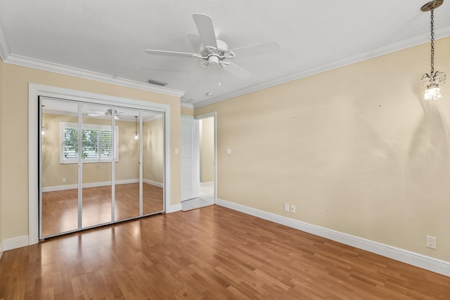 unfurnished bedroom with crown molding, hardwood / wood-style flooring, and a closet