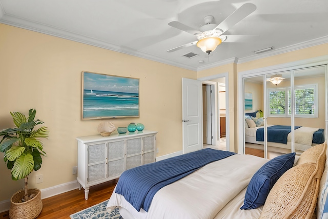 bedroom featuring crown molding, dark wood-type flooring, ceiling fan, and a closet