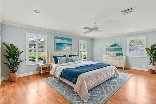 bedroom with multiple windows, crown molding, and light wood-type flooring