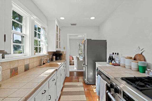 kitchen featuring white cabinetry, backsplash, sink, and light tile patterned floors