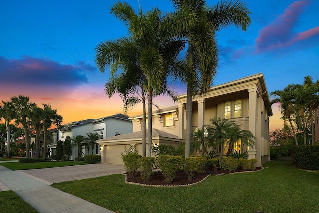 mediterranean / spanish-style house featuring a front yard, decorative driveway, stucco siding, and an attached garage