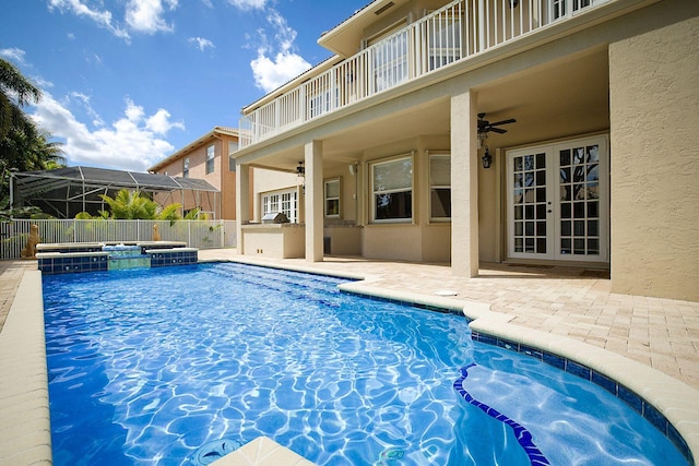 view of pool featuring a pool with connected hot tub, a patio area, french doors, a ceiling fan, and fence