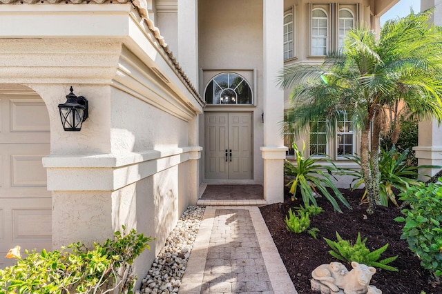 property entrance featuring a garage and stucco siding