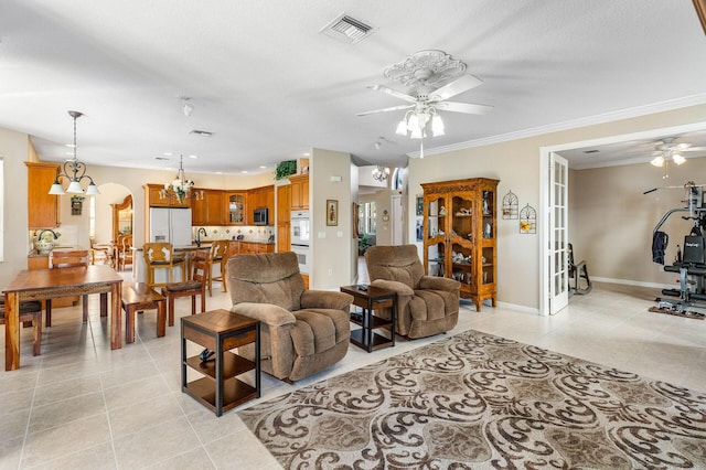 living room featuring light tile patterned floors, visible vents, arched walkways, and ceiling fan with notable chandelier