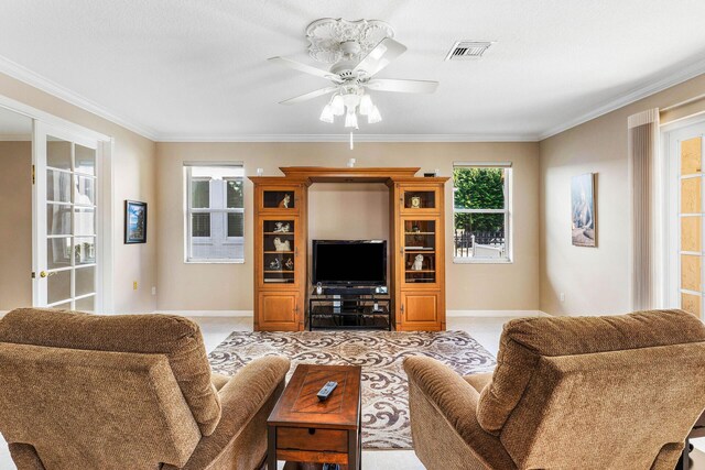 living room featuring baseboards, visible vents, ornamental molding, and a ceiling fan