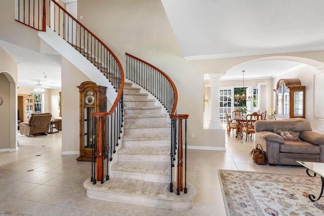 staircase with ornamental molding, baseboards, a high ceiling, and tile patterned floors