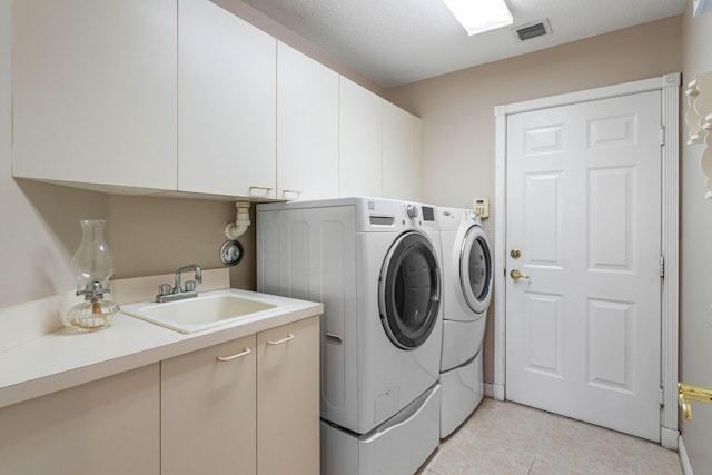 laundry area with washing machine and clothes dryer, visible vents, a sink, cabinet space, and light tile patterned floors